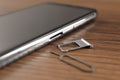 SIM card tray, mobile phone and ejector tool on wooden table, closeup