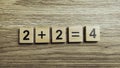 Simple addition math equation two plus two equals four using wooden number tiles on wood background Royalty Free Stock Photo