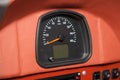 Analog car speedometer with a red arrow on a leather trimmed panel