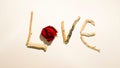 Simple art concept representing love written with wooden sticks and a red rose on white background