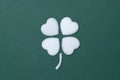 Simple art flatlay of a four leaf clover or cloverleaf made with a white heart on a forrest green background.