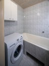 Simple bathroom interior in modern apartment. White bath and tile. Washing machine