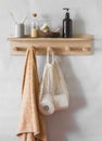 Simple bathroom - wooden shelf with a towel, shampoo, eco bag with toilet paper, flower. Minimalism style