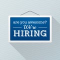 Simple blue sign with text `we`re hiring` hanging on a gray office wall. Human Resources, employment concept Royalty Free Stock Photo