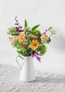 A simple bouquet of autumn flowers in an enamel vintage jug on a table in a bright room. Copy space