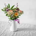 Simple bouquet of autumn flowers in an enamel vintage jug on a table in a light room. Copy space