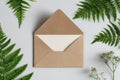 simple brown envelope placed on light surface, framed by lush green ferns and delicate white flowers. This setting creates serene Royalty Free Stock Photo