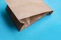 Simple brown paper bag for lunch or food on table. Craft paper bag on bright blue background. Zero waste organic concept Royalty Free Stock Photo