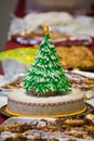 Simple cake dekorated with an eatable christmas tree pops out amonst other pies and cakes on a christmas party