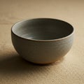 A simple ceramic bowl with a grey, speckled surface, resting on a textured beige Royalty Free Stock Photo