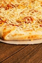 Simple cheese pizza on a cardboard base on a wooden table surface. Frozen product. Italian style fast food Royalty Free Stock Photo