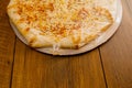 Simple cheese pizza on a cardboard base on a wooden table surface. Frozen product. Italian style fast food Royalty Free Stock Photo