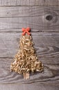 Simple Christmas tree arranged from sawdust, wood-chips on wooden background. Orange cute ribbon. Royalty Free Stock Photo