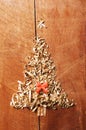 Simple Christmas tree arranged from sawdust, wood-chips on wooden background. Orange cute ribbon Royalty Free Stock Photo