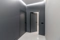 Simple clean newly built generic modern new real estate block of flats interior, long black corridor with black doors, perspective