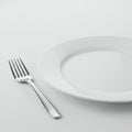 A simple composition featuring a clean, white porcelain plate on a smooth, light-colored surface.