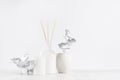 Simple contemporary white decorations for interior - aromatic white diffuser with sticks, ceramic vase with silver leaves.