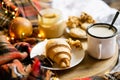 Simple country home breakfast in bed, coffee with milk and homemade pastry on plaid blanket Royalty Free Stock Photo