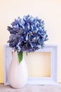 Simple design of hydrangea flowers in a vase with a white picture frame against a yellow painted background Royalty Free Stock Photo