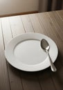 A simple dining arrangement features a plain white ceramic plate with a stainless steel spoon Royalty Free Stock Photo