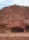 Simple dwelling ruins - cave like holes in stone wall, Jordan flag waves on top, typical Petra scenery Royalty Free Stock Photo