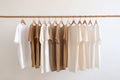 Simple elegant organic cotton t-shirts on hangers hanging on tree branch wood rack. Zero waste recycled material sustainability