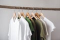 Simple elegant organic cotton t-shirts on hangers hanging on tree branch wood rack. Zero waste recycled material sustainability