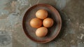 Top view of fresh, organic raw chicken eggs on a rustic brown ceramic plate Royalty Free Stock Photo