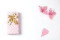 Simple flat lay composition. gift box of pink color with a bow of gold , a decoration in the form of a heart covered with a