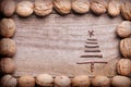 Simple frame arranged from walnuts on wooden background with Christmas tree made from sticks, twigs, driftwood. Royalty Free Stock Photo