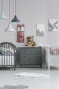 Simple, gray and white room interior for two little children with a chest of drawers between two wooden beds. Real photo Royalty Free Stock Photo