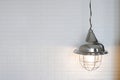 Simple hanging lamp on a rope hanging by a bed with white bedclothes. Electric lamp is modern and vintage object interior,