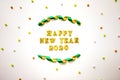 Simple happy new years 2020 text in gold lettering, curled ribbon and colorful beads isolated on white background