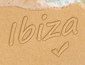 Simple Ibiza Spanish holiday getaway message written in smooth sand with an incoming wave on a tropical beach Royalty Free Stock Photo