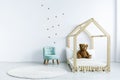 Simple kid room interior with diy bed with a teddy bear, armchair, round rug and stars on the wall. Place for your product Royalty Free Stock Photo