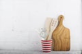 A simple kitchen still life against a white brick wall: cutting board, cooking equipment, ceramics. Horizontal