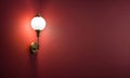 Simple lamp hangs on red wall and illuminates it, space for text