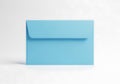 A simple light blue square envelope with a folded flap sits on a clean light gray surface casting a subtle shadow Royalty Free Stock Photo