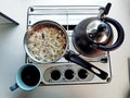 Simple and minimalistic breakfast vintage style with muesli, tea kettle and a mug of coffee on a gas stove kitchenette