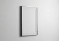 A simple modern rectangular mirror with a thin metallic frame hangs on a plain white wall reflecting a blank space Royalty Free Stock Photo