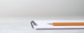 A simple notepad with a pencil resting on it set against a blurred background conveying a clean and minimalistic workspace