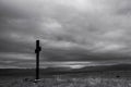 Simple oak catholic cross on  field, storm clouds over  mountains Royalty Free Stock Photo