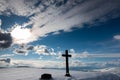 Simple oak wood catholic cross at the top of the mountain, sunset at wintertime