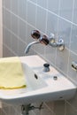 Simple old tiled bathroom and sink with various cleaning supplies Royalty Free Stock Photo