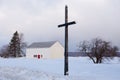 Simple old wood cross with red and white barn in soft focus background seen during a late winter blue hour early morning Royalty Free Stock Photo