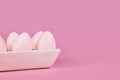 Simple one colored Easter eggs in egg tray on pink background Royalty Free Stock Photo