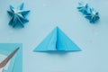 Simple origami 3D Christmas tree made from blue paper. Step by step instruction, step 12
