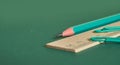 A simple pencil, a wooden ruler, and two paper clips lie on a plain green background. Close up Royalty Free Stock Photo