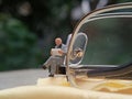 Simple Photo Conceptual Photo Mini Figure Old Man Toy Sitting and Reading News Paper, Journal or Book at black Plastic eyeglass, Royalty Free Stock Photo