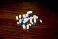 Simple pile of white and blue pills, medicines, pills stacked on brown background Royalty Free Stock Photo